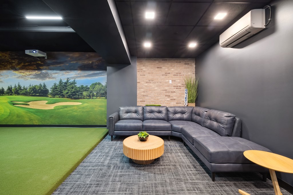 A golf simulator room with a large lounge couch.