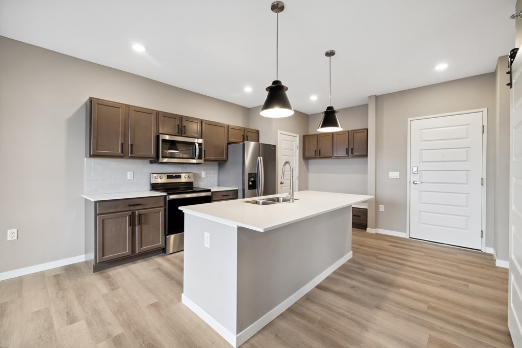 A kitchen with island and brown cabinets.