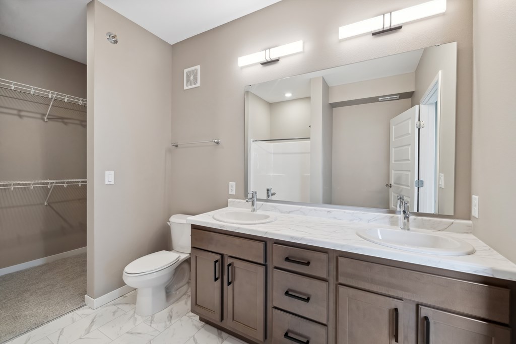 A bathroom with double vanity with wood-toned cabinets.
