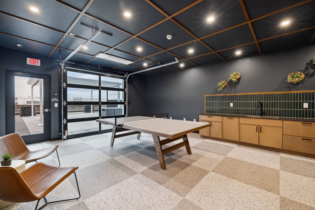 A room with a ping pong table and garage door.