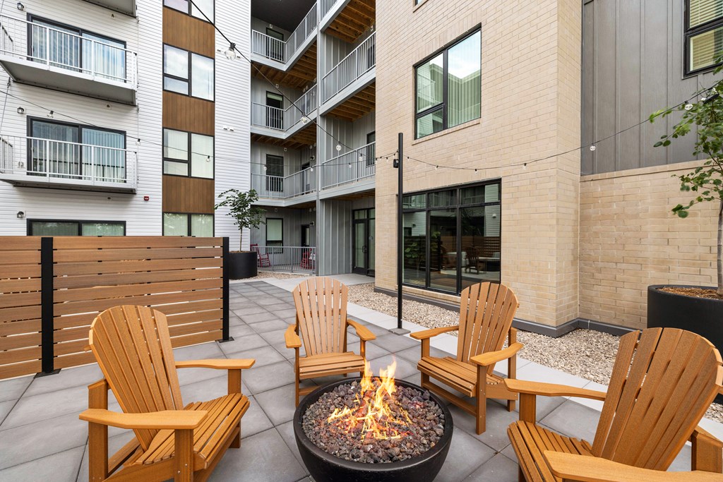 A fire pit sits in the middle of a patio surrounded by chairs.