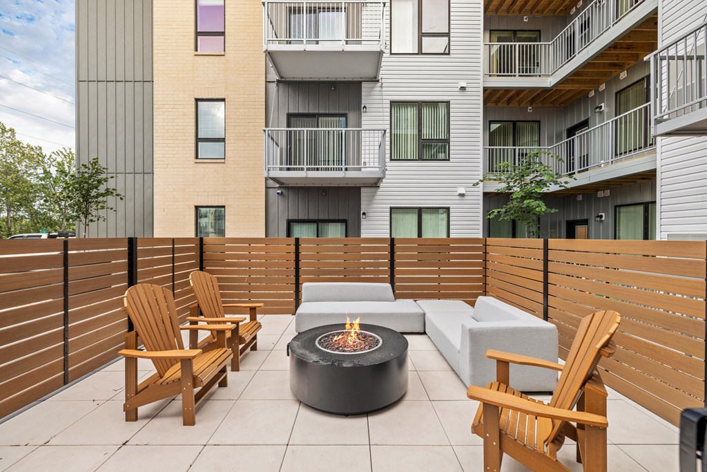 A patio with a fire pit, chairs and a couch.