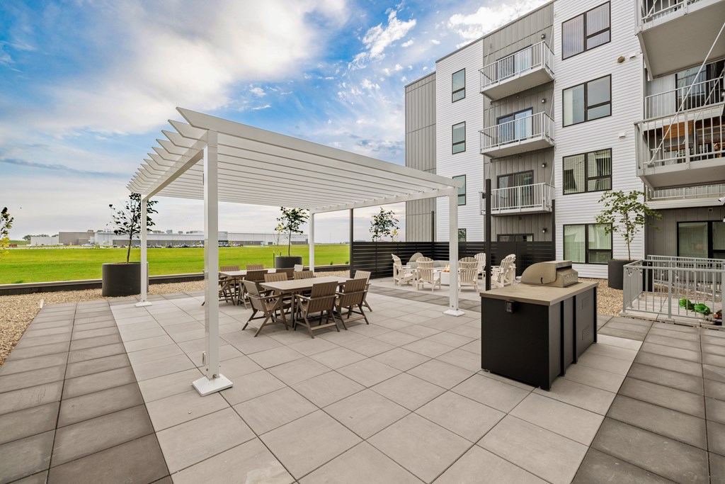 A patio with a table and chairs under a white pergola.