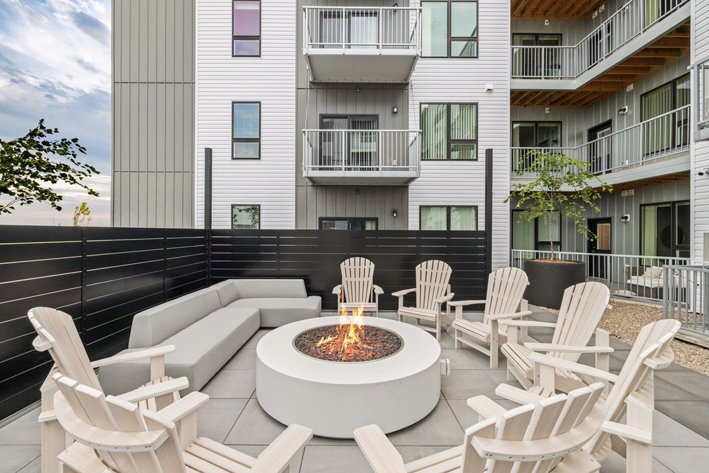 A modern patio with a fire pit and chairs.