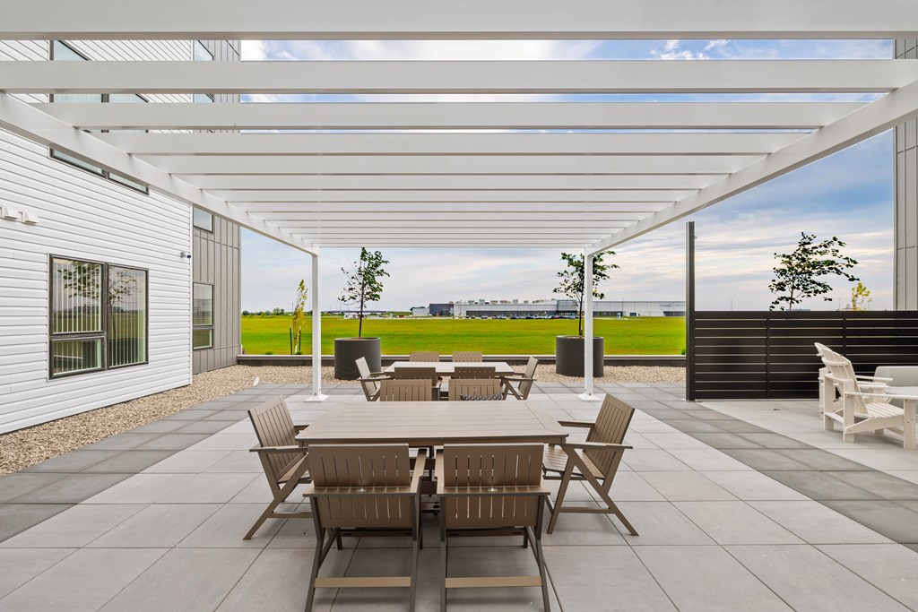 A patio with a table and chairs is covered by a white roof.