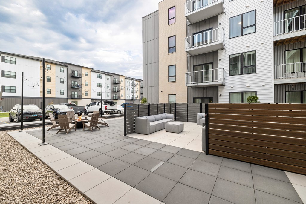 A modern apartment complex with a patio area in the foreground.