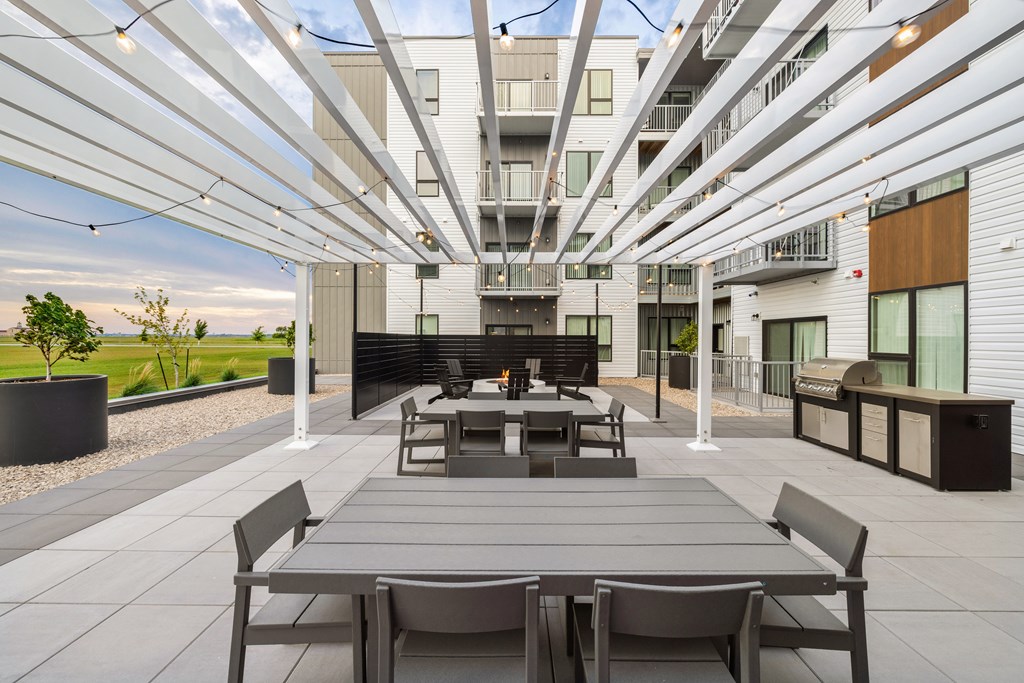 A modern outdoor seating area with a long table and chairs.