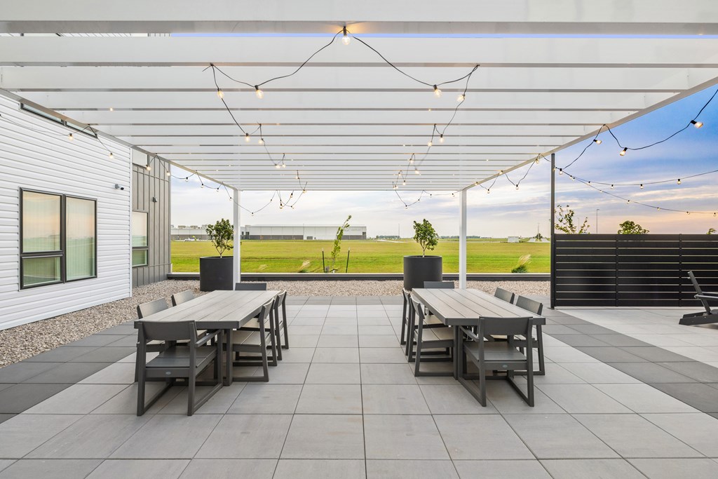 A patio with two tables and chairs under a white roof.