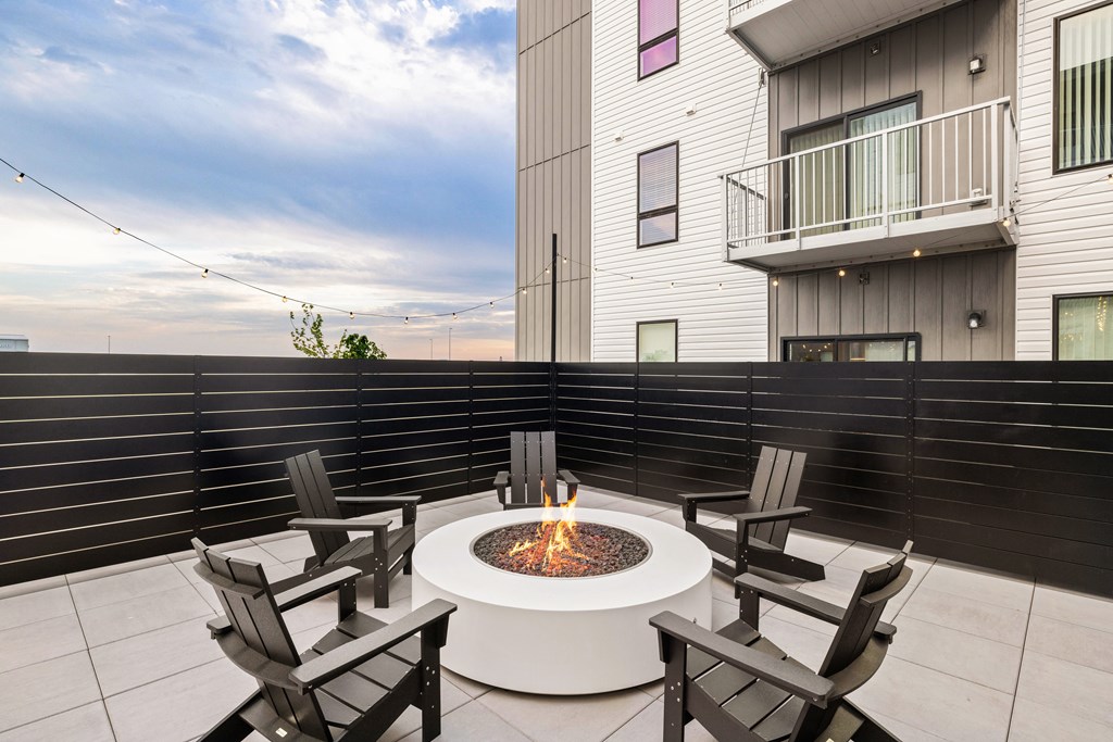 A fire pit on a patio surrounded by chairs.