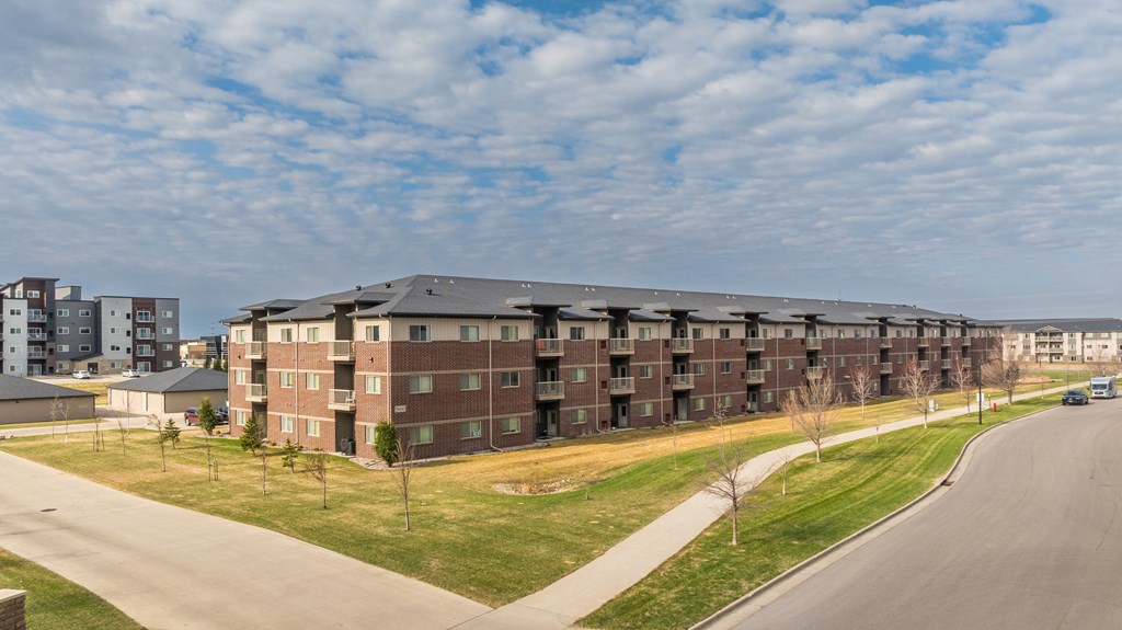 A large apartment complex with a road in front of it.