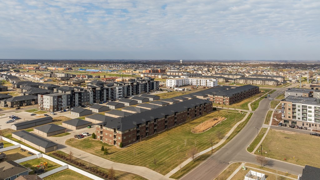 A large apartment complex is surrounded by smaller buildings and a road.