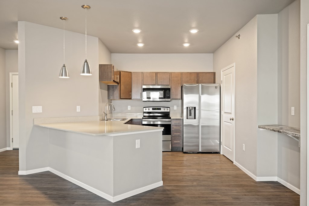A kitchen with a white counter top and stainless steel appliances.