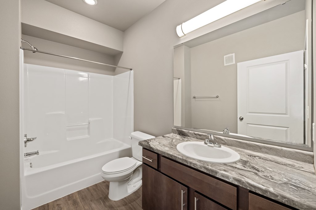 A white bathroom with a marble countertop and a white toilet.