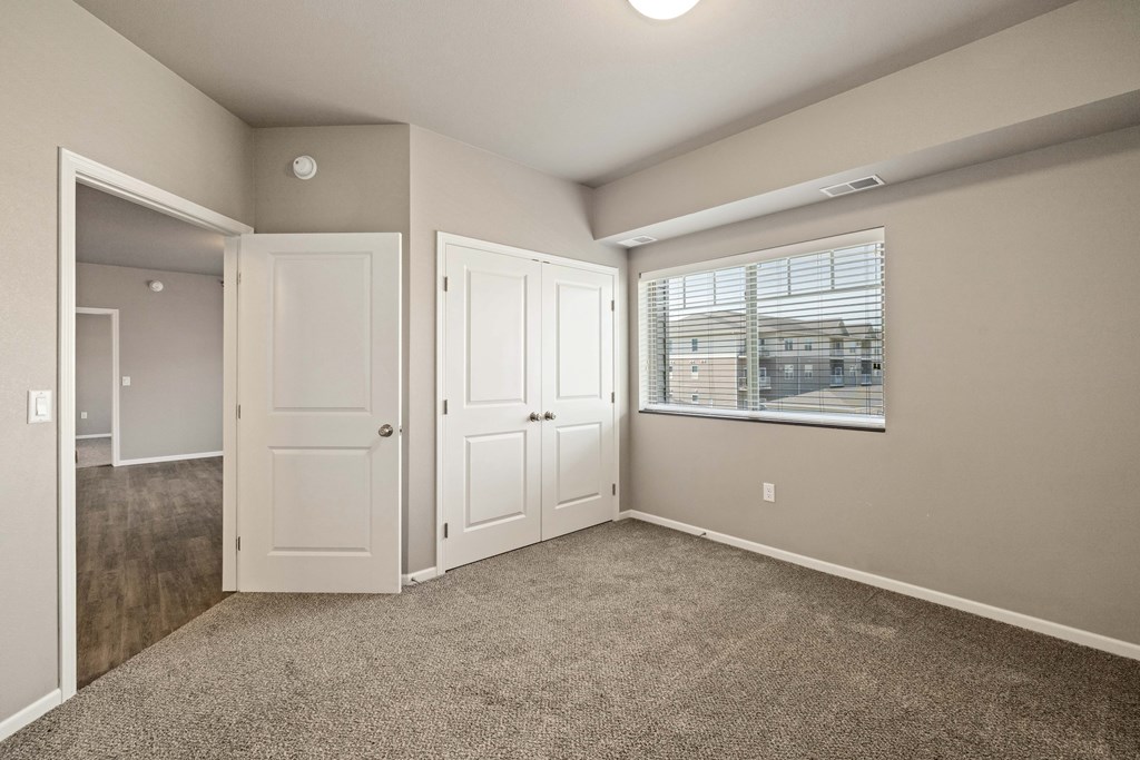 A room with a carpeted floor and a window with blinds.