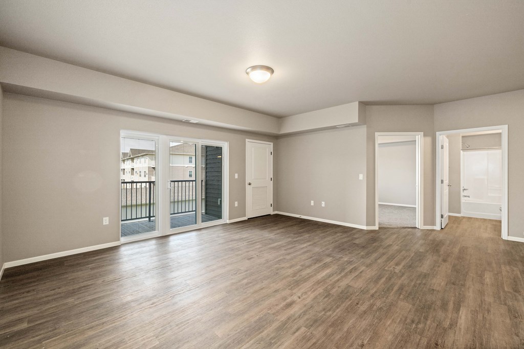 A spacious room with wooden flooring and white walls.