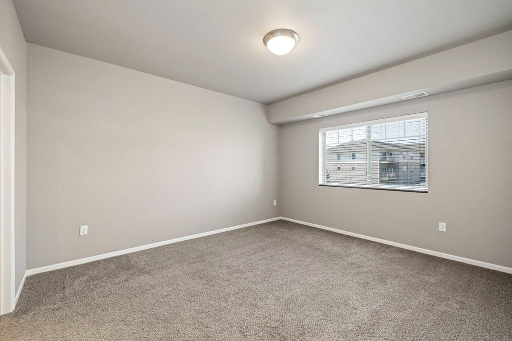 A room with a window and carpeted floor.
