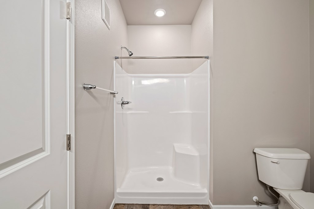 A white bathroom with a toilet and a walk-in shower.