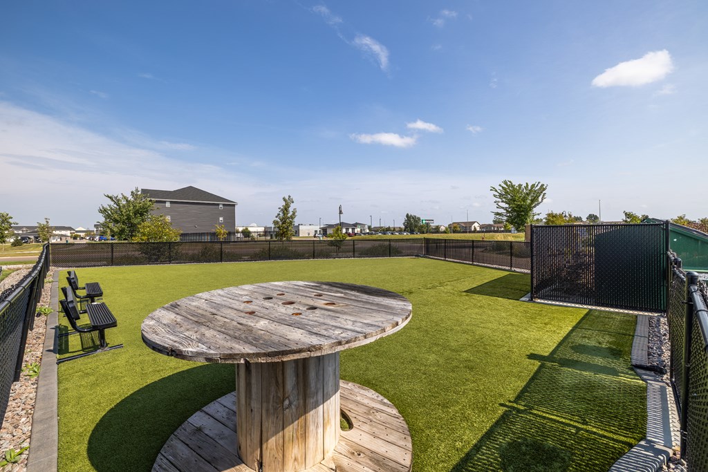 A wooden table sits in the middle of a grassy area.