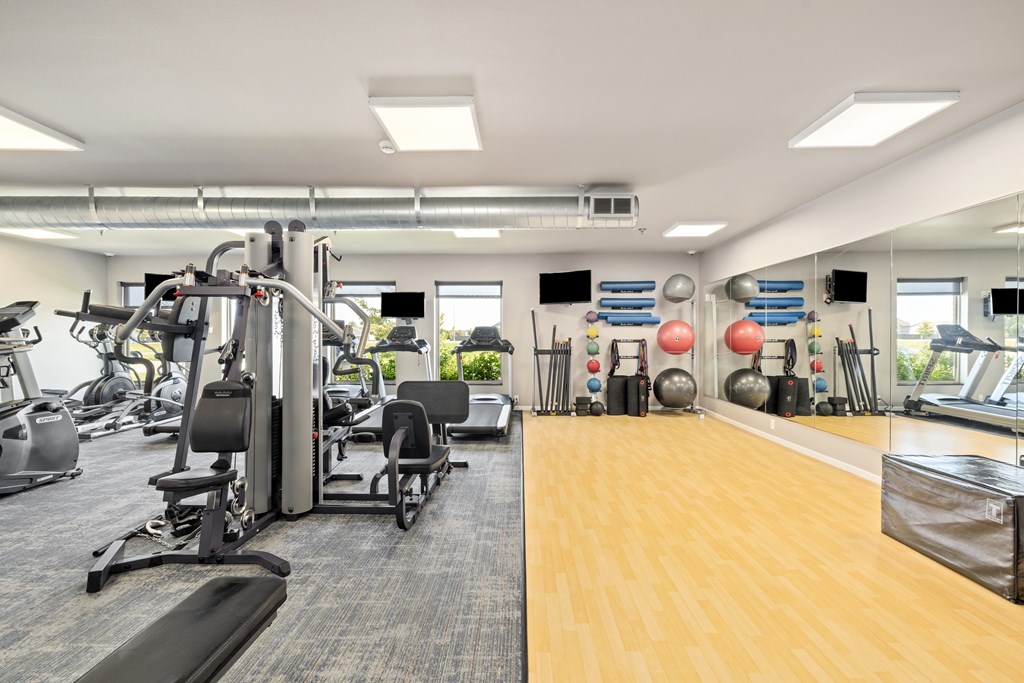 A gym with a variety of equipment including treadmills, weights, and exercise machines.