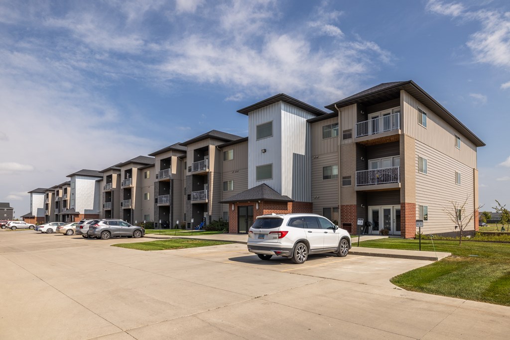 A row of modern apartment buildings with cars parked in front.