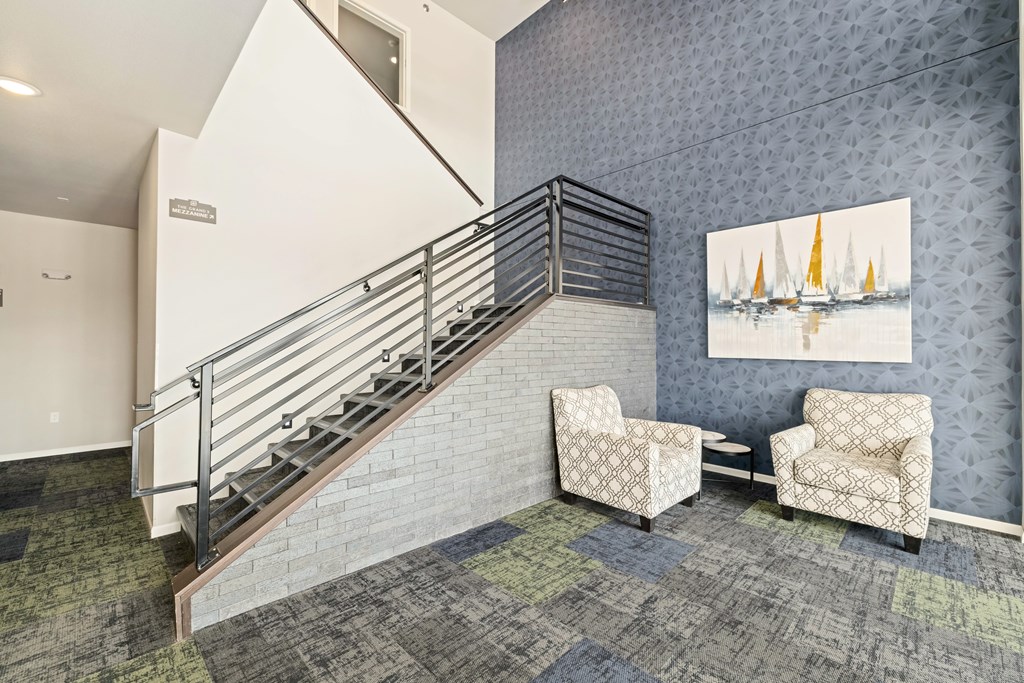 A staircase with a metal railing and a painting of sailboats on the wall.