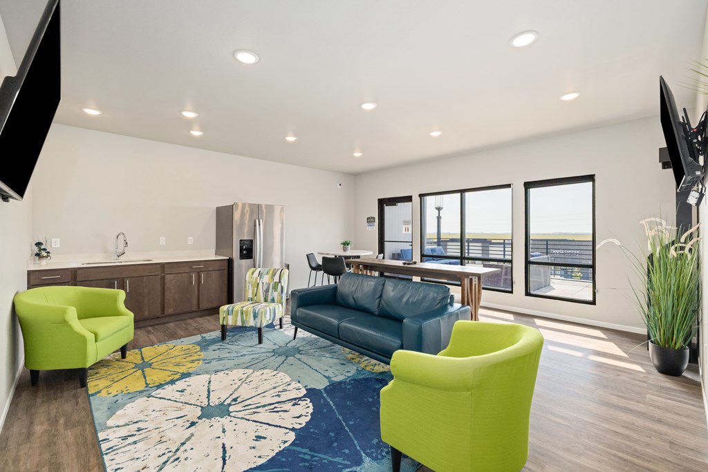 A living room with a blue couch, yellow chairs, and a rug with a circular design.