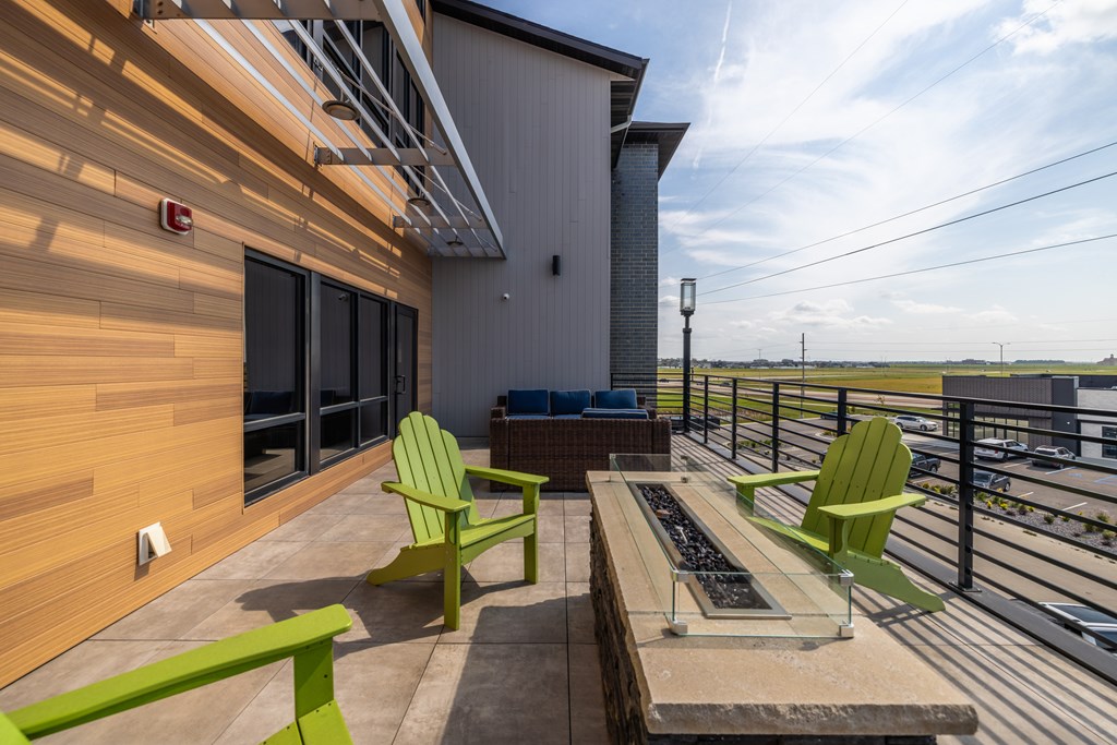 A balcony with green chairs and a table.