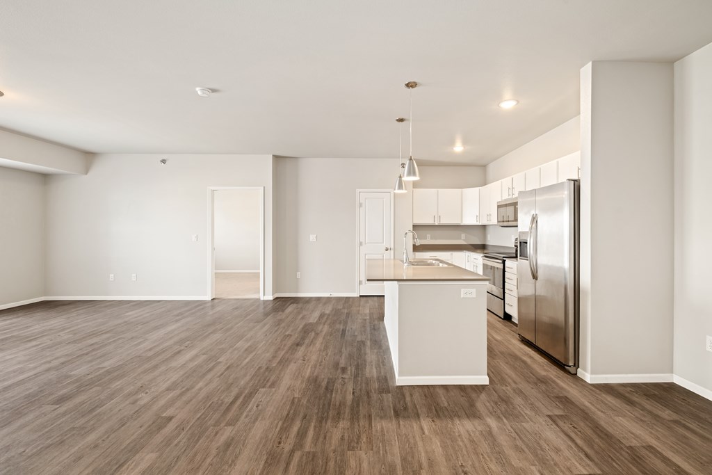 A kitchen with white cabinets and a wooden floor.