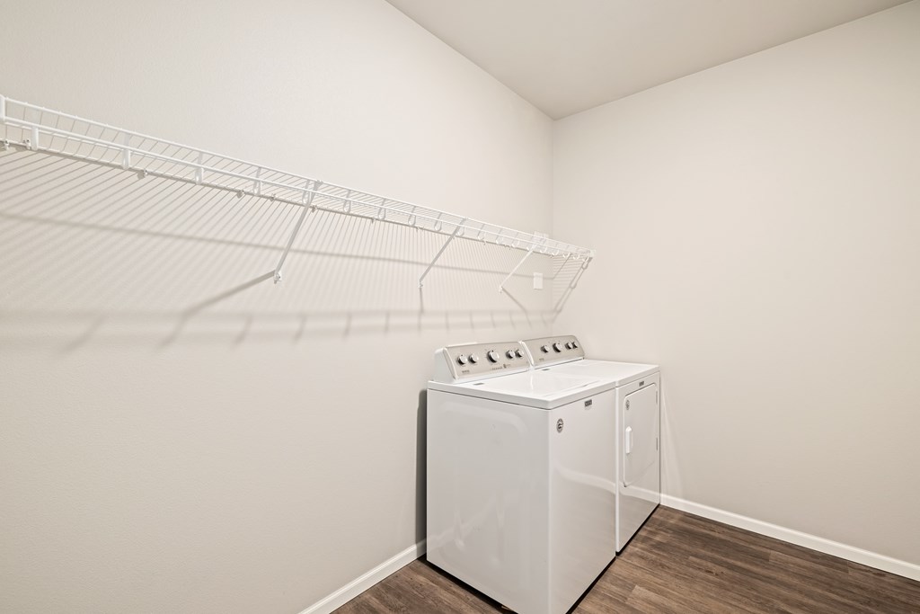 A white dryer is sitting in a room with a white wall and a white shelf.