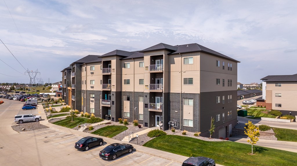 A modern apartment complex with cars parked in the driveway.