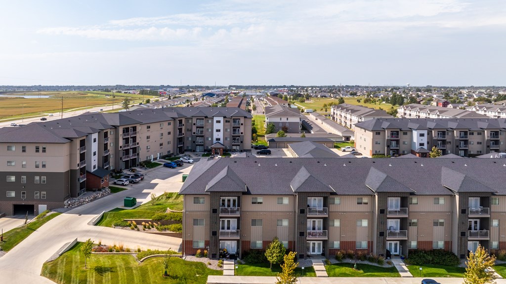 Apartment complex with a mix of beige and brown buildings with green lawns in front.