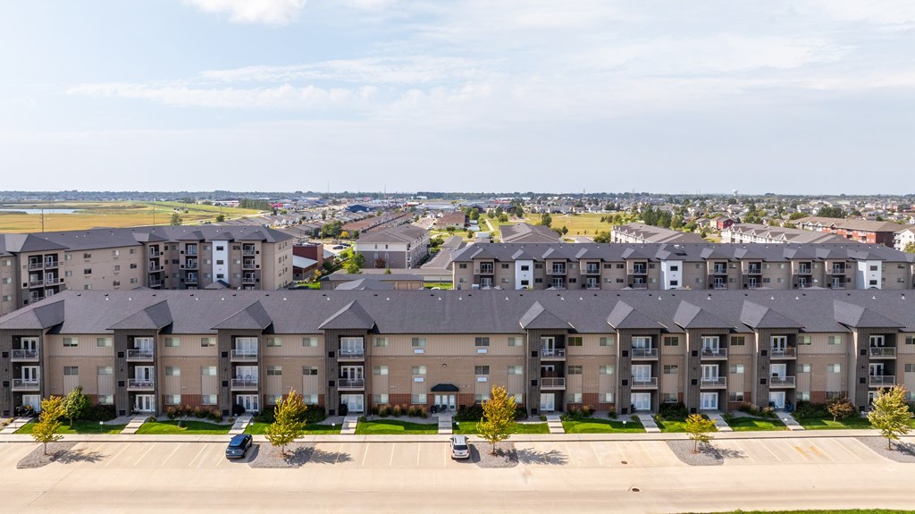 Apartment complex with a parking lot in front.
