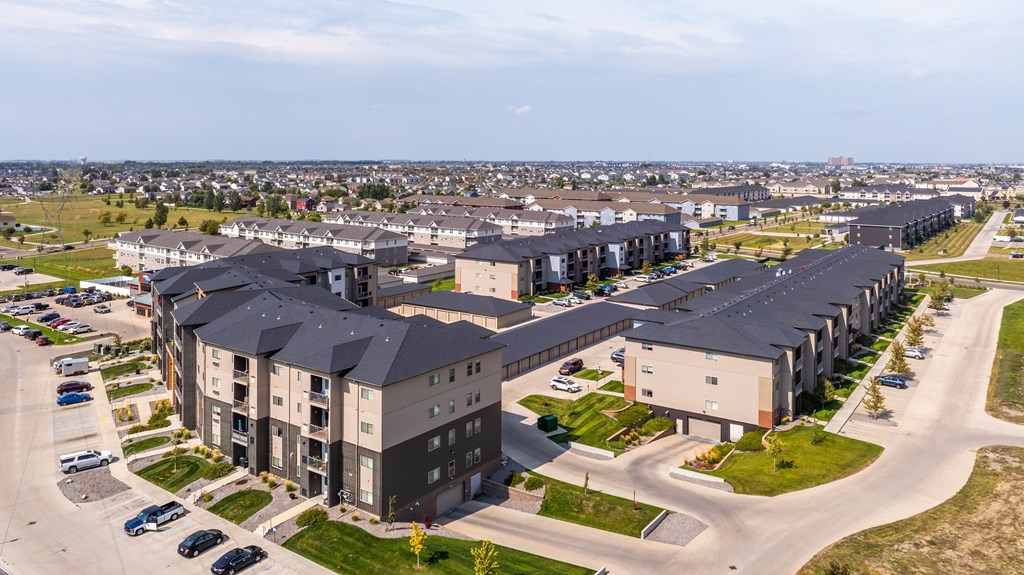 A large apartment complex with multiple buildings and a parking lot in front.
