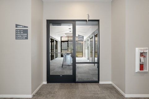 A hallway with a sign on the wall that says "Floor 1" and "Work Pods".