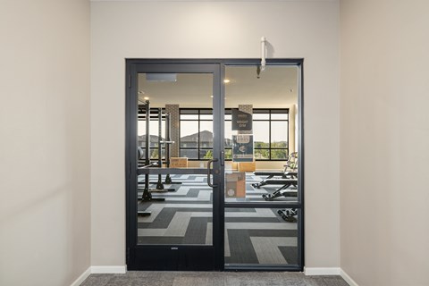A black door with a glass window is open to a room with a black and white checkered floor.