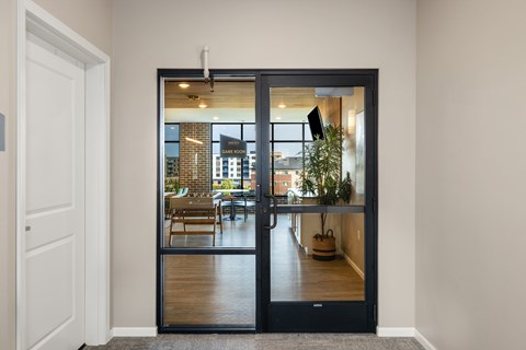 A black door with a glass window leads to a dining room.