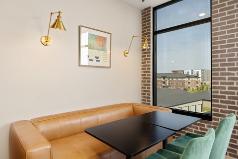 A brown leather couch with a black table in front of a window with a view of a building.