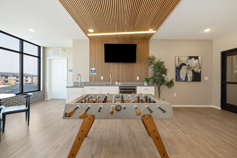 A foosball table in the middle of a room with a tv mounted on the wall.