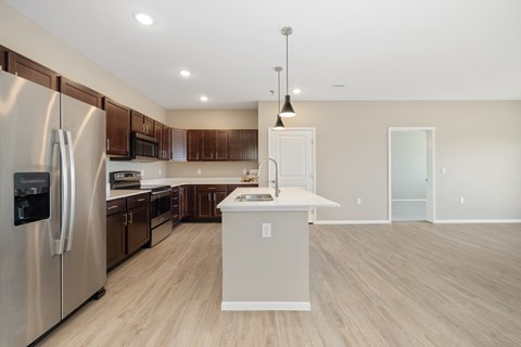 A modern kitchen with a refrigerator, microwave, and oven.