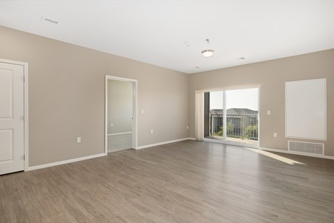 A large empty room with wooden flooring and white walls.