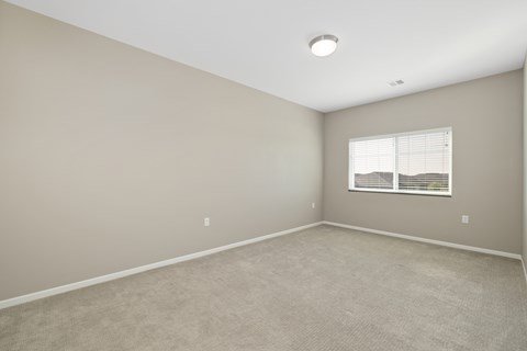A room with a window and carpeted floor.