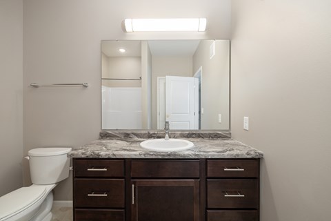 A bathroom with a granite countertop and a white toilet.