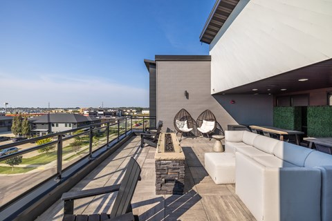 A modern outdoor seating area with white couches and a wooden deck.