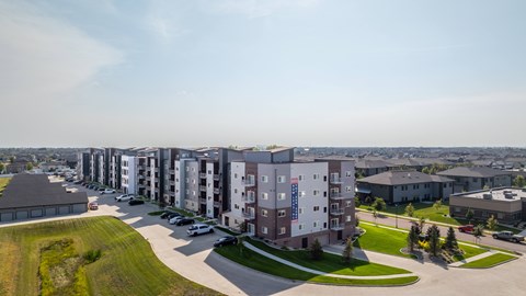 A row of apartment buildings with a parking lot in front.
