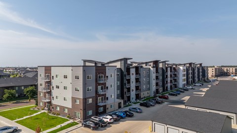 A row of apartment buildings with cars parked in the driveways.