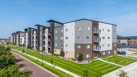 A row of modern apartment buildings with green lawns in front.