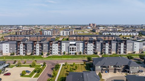 A large apartment complex with a parking lot in front.