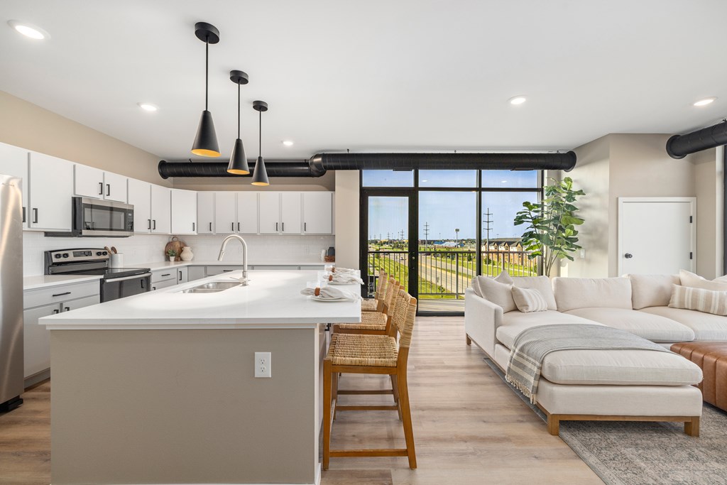 A modern kitchen with a large island and a dining area with a view.