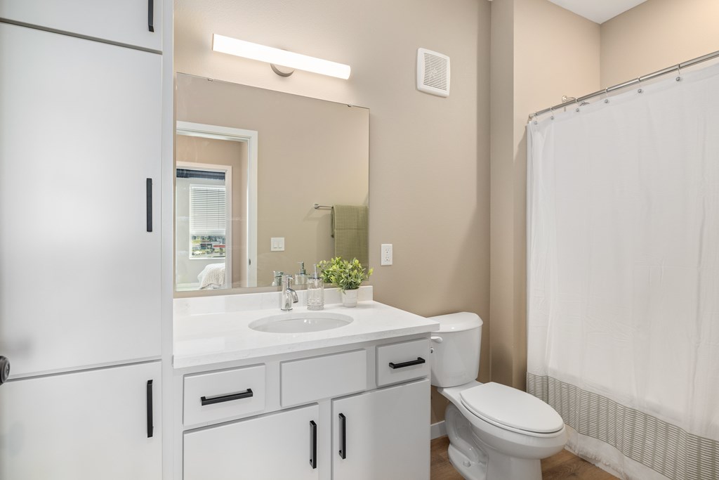 A white bathroom with a toilet, sink, and shower.