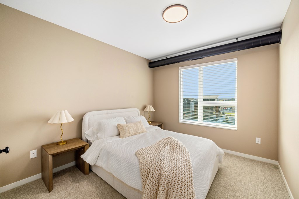 A bedroom with a bed, nightstand, and window.